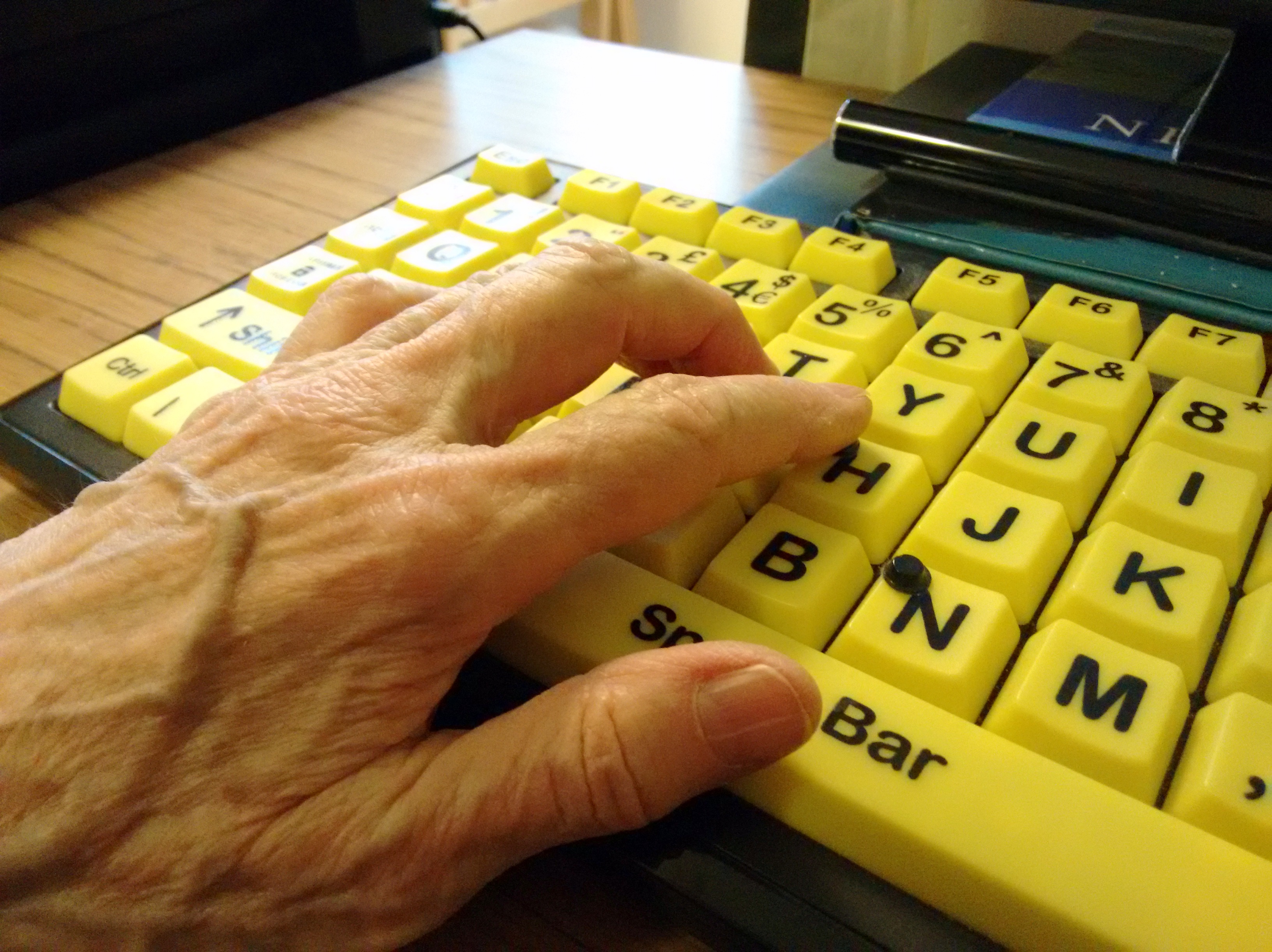 A hand rests on a high-contrast accessible computer keyboard.