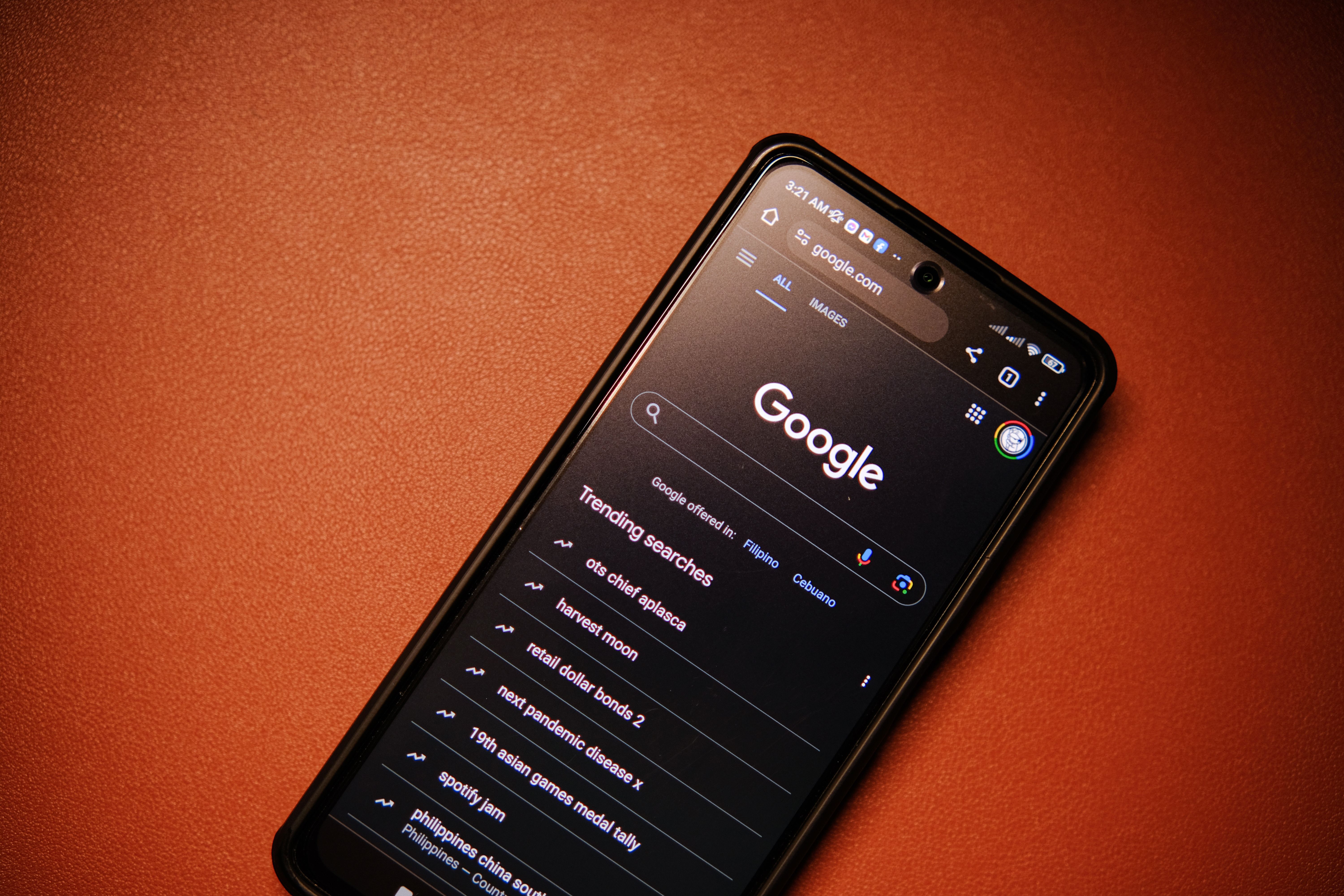 Ponsel pintar menampilkan tren pencarian Google di atas meja pada malam hari