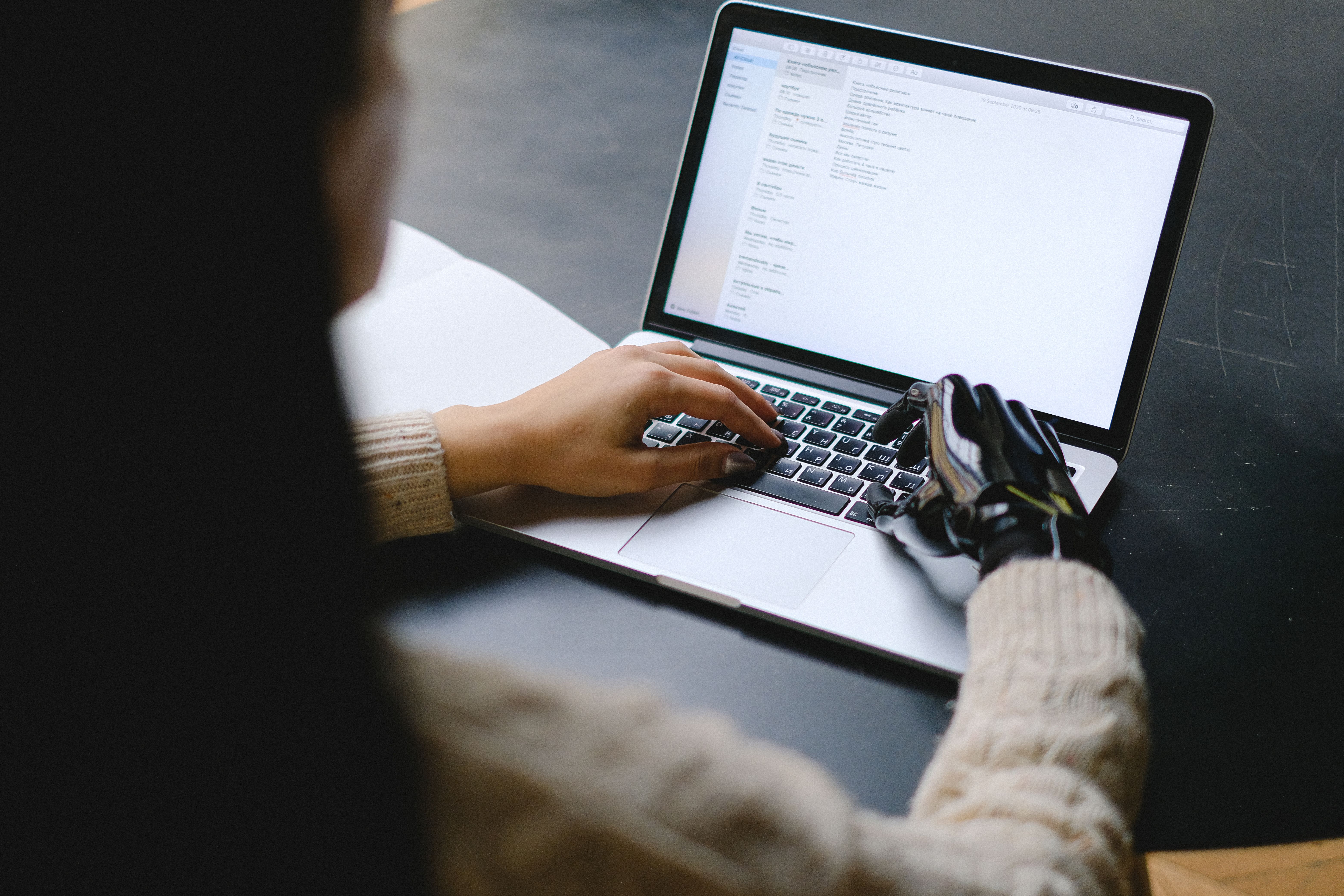 A person using a laptop keyboard at a desk.