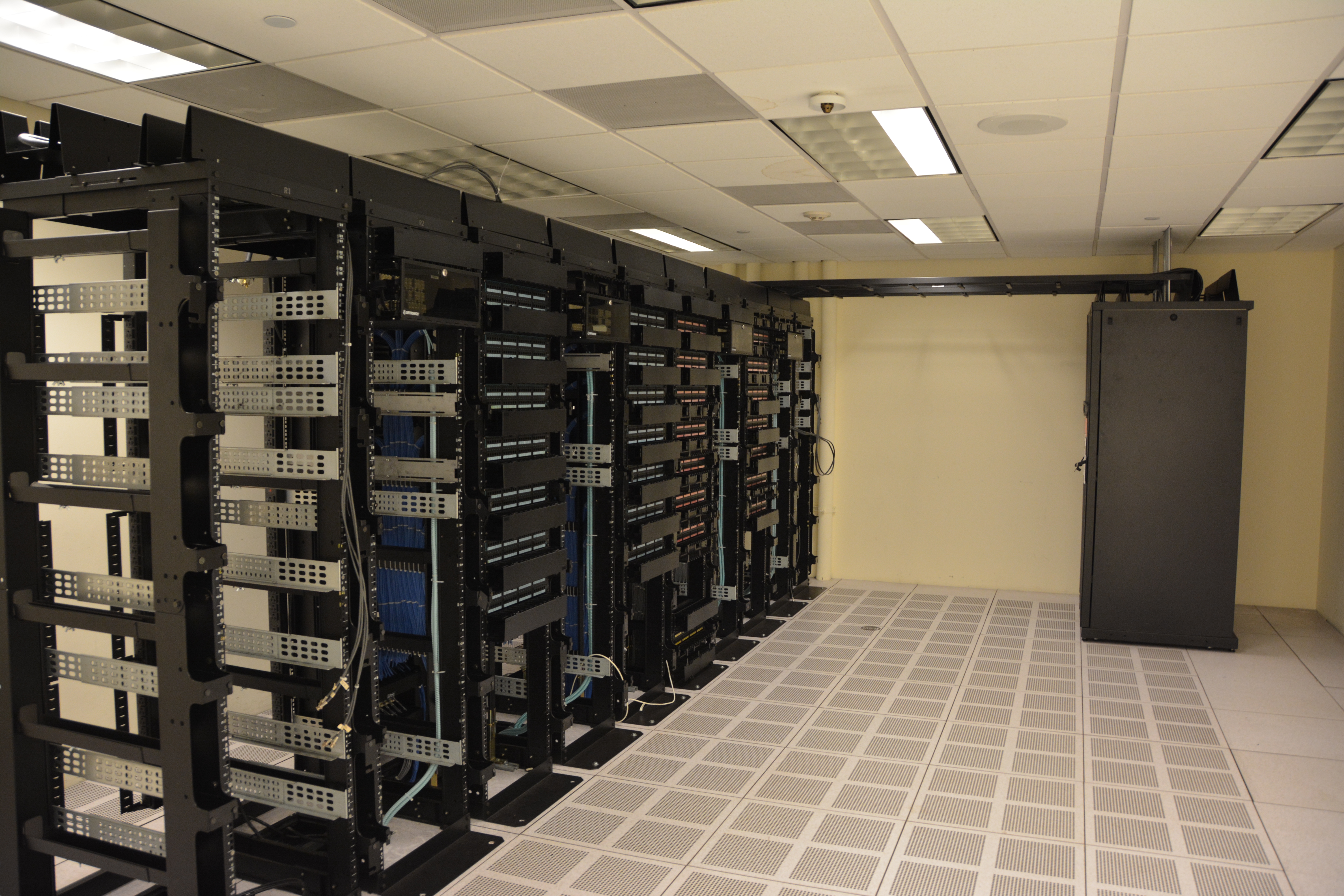 Rows of tall server racks illuminated with network activity lights in a modern enterprise datacenter