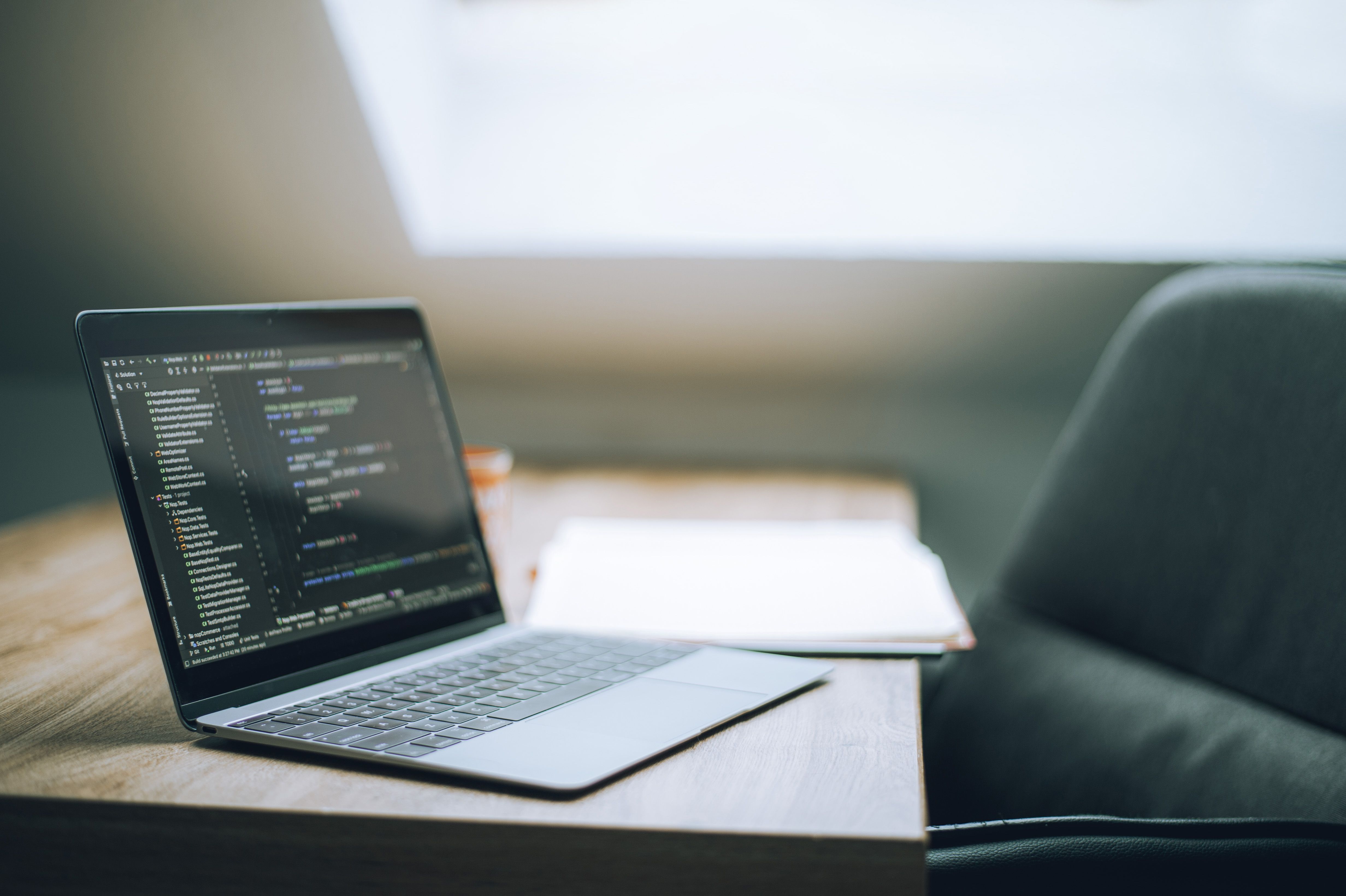 Open laptop displaying code on a desk in a bright modern office setting.