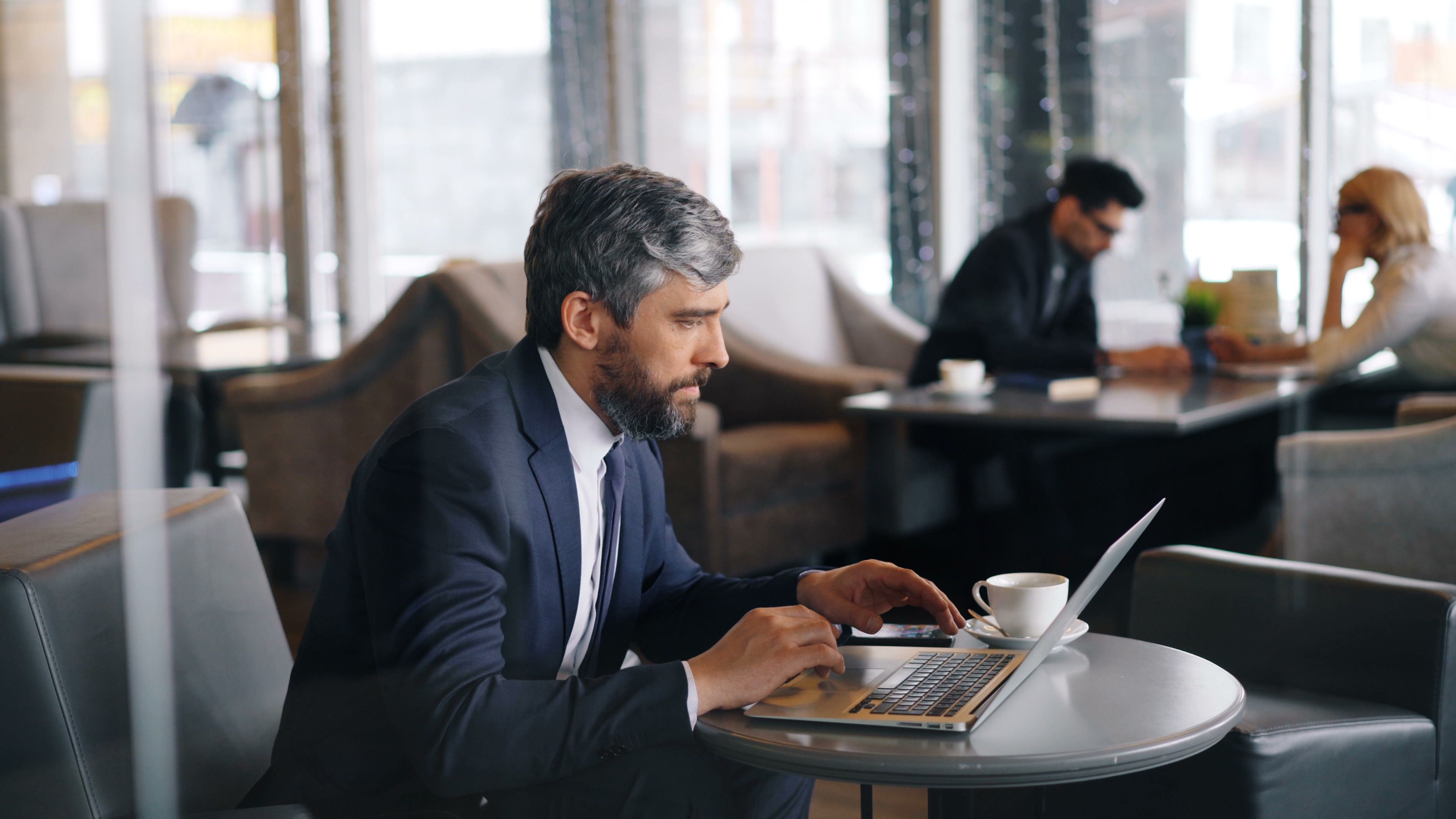 Business professional working on a laptop in a contemporary cafe.