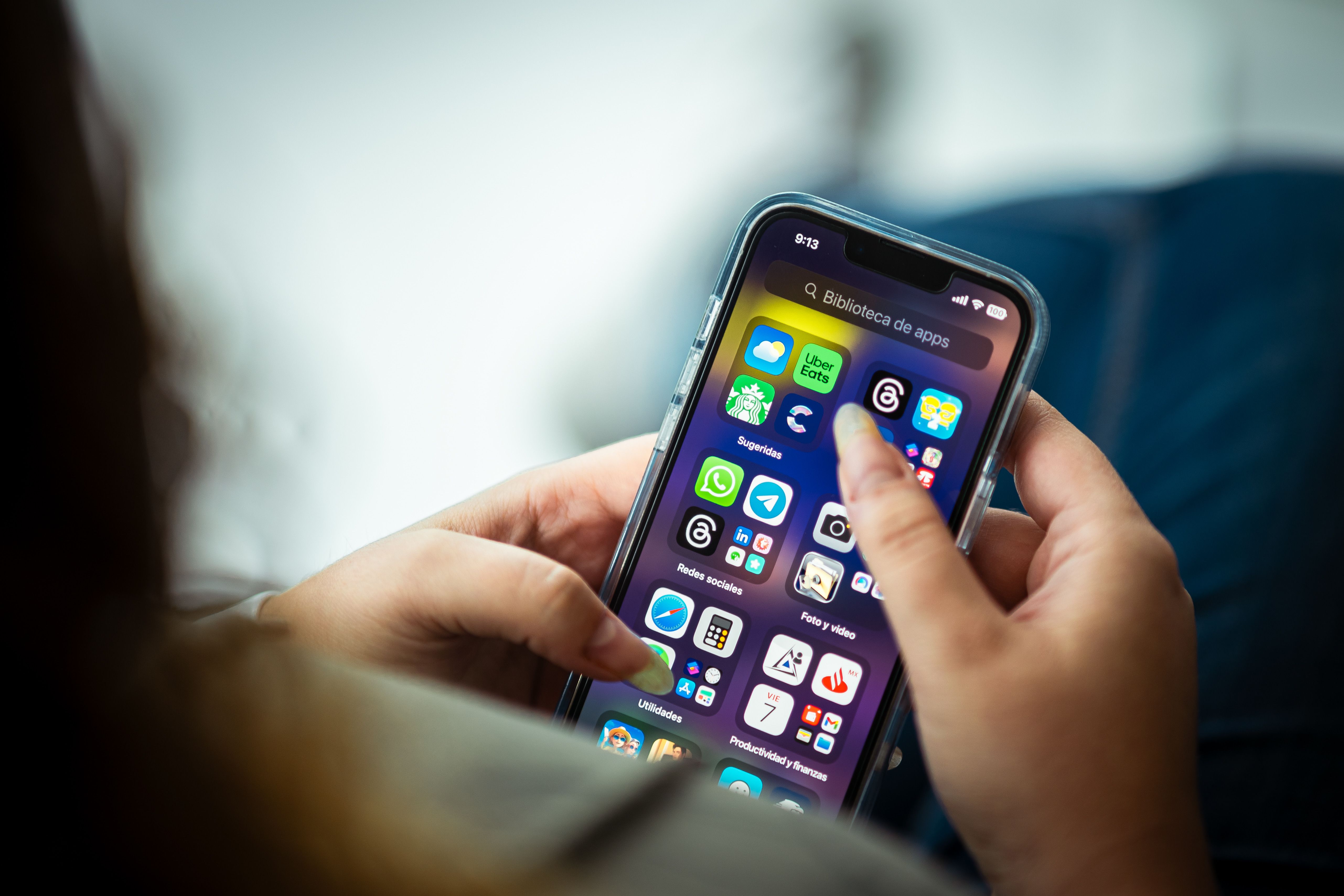Photo illustration of a person holding a smartphone displaying various app icons