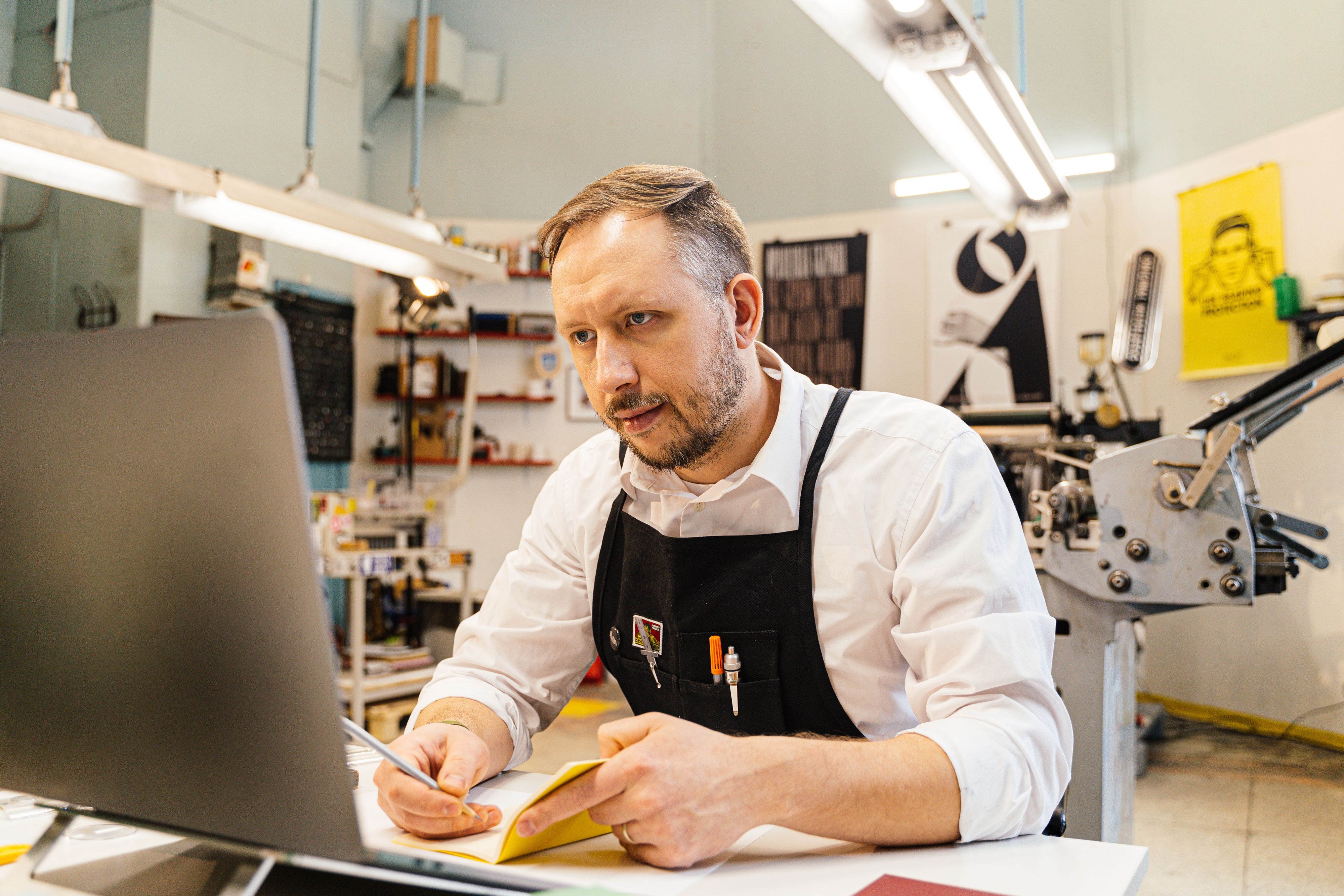 Illustrative photo of a focused worker using a laptop in a busy workspace.