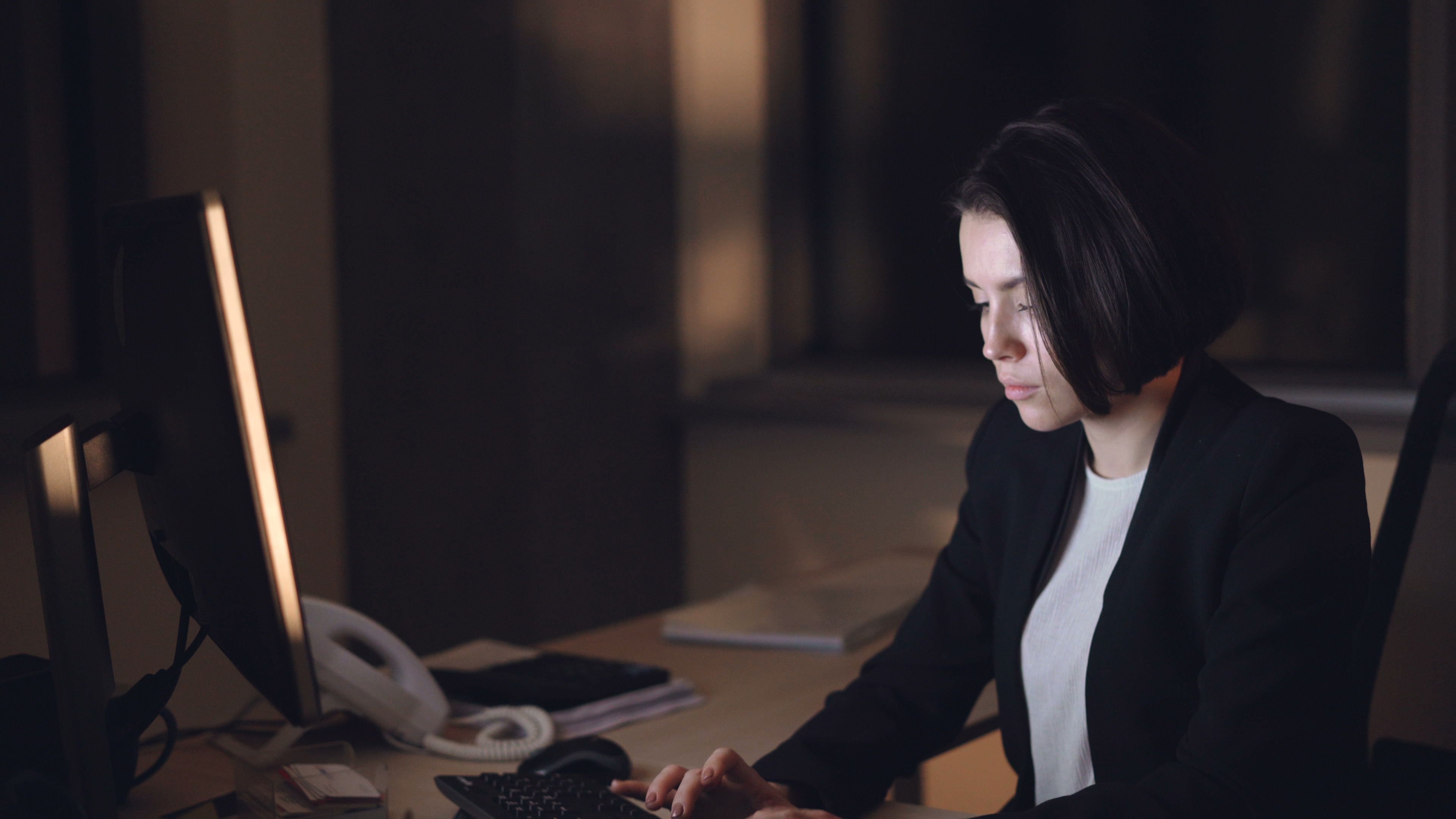 Illustrative photo of a professional working at a computer in a dim office
