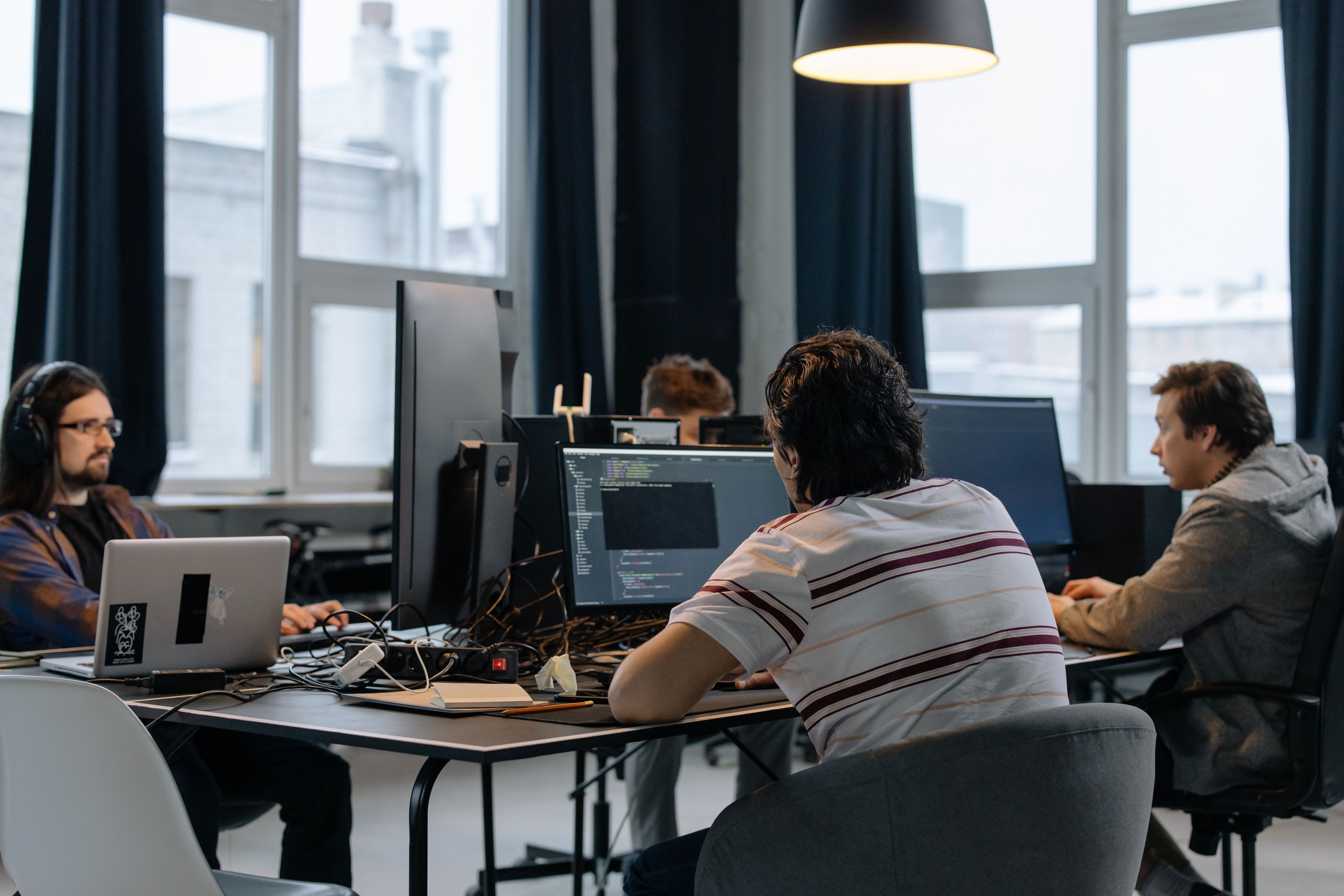 Software engineering team working together on computers in a modern tech office setting.