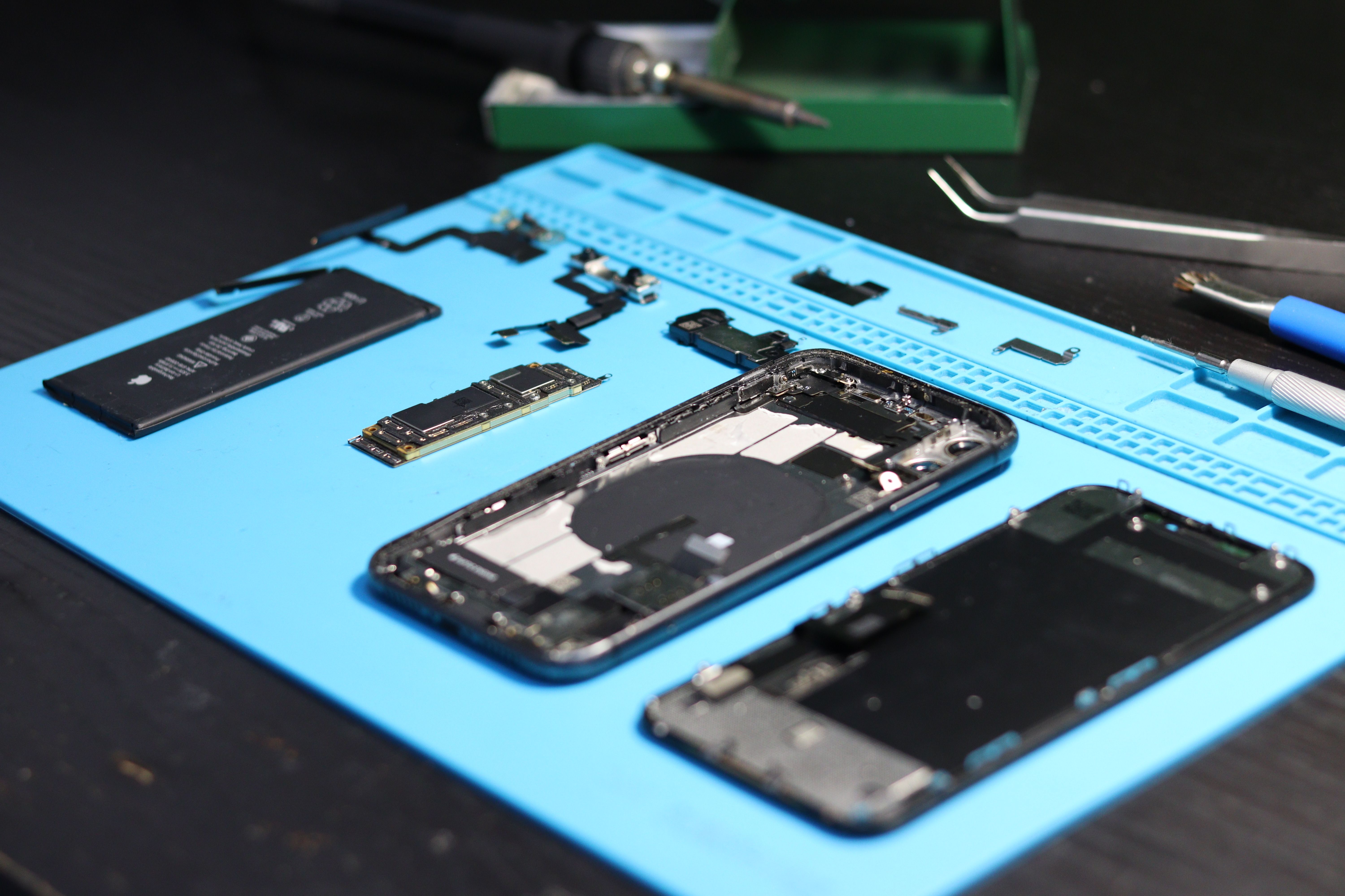 Disassembled smartphone and precision screwdrivers on an electronics repair workbench.