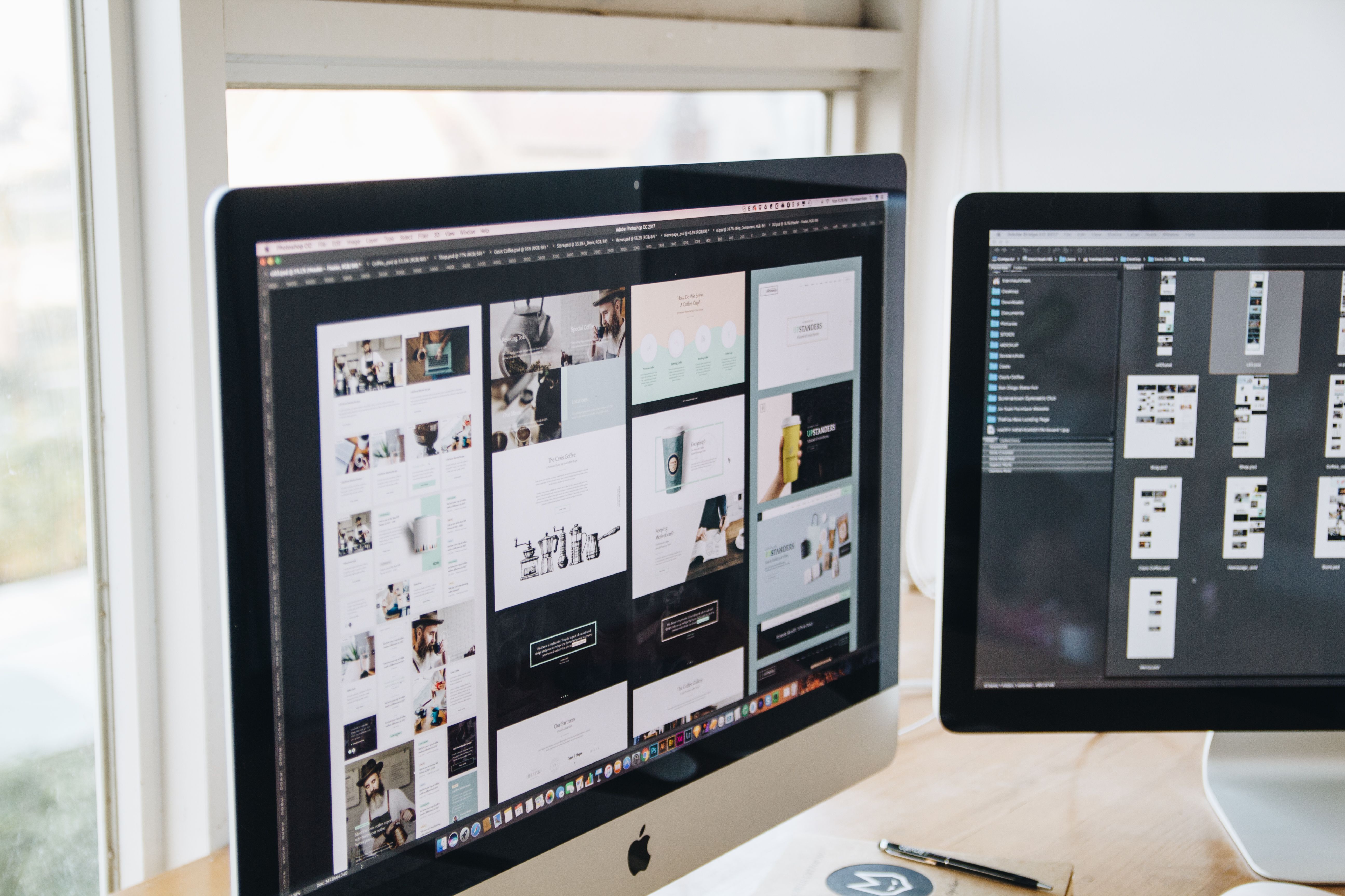 Modern designer workstation with dual monitors displaying design tools and typographic layout systems.