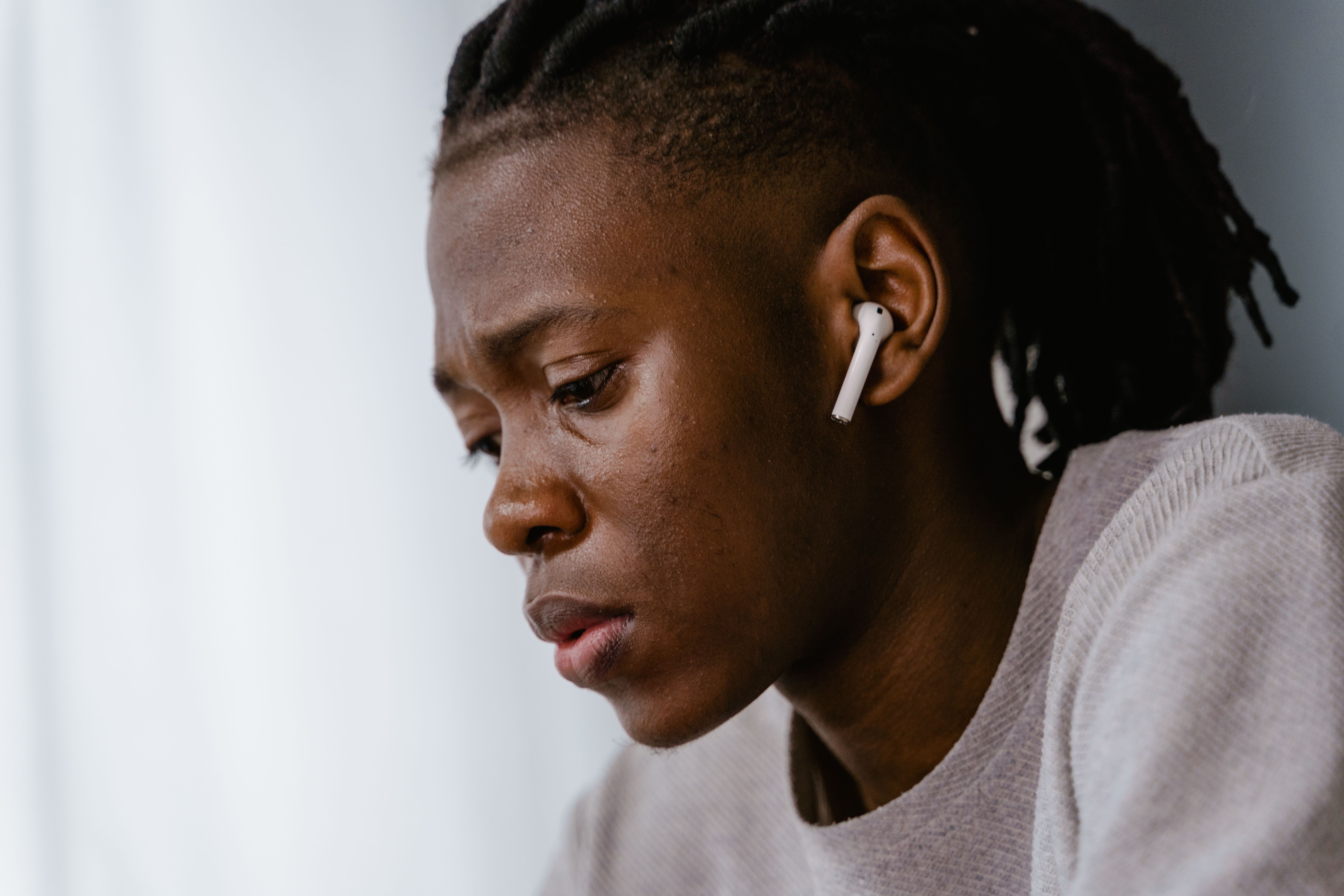 Close-up profile of a focused individual wearing wireless earbuds.