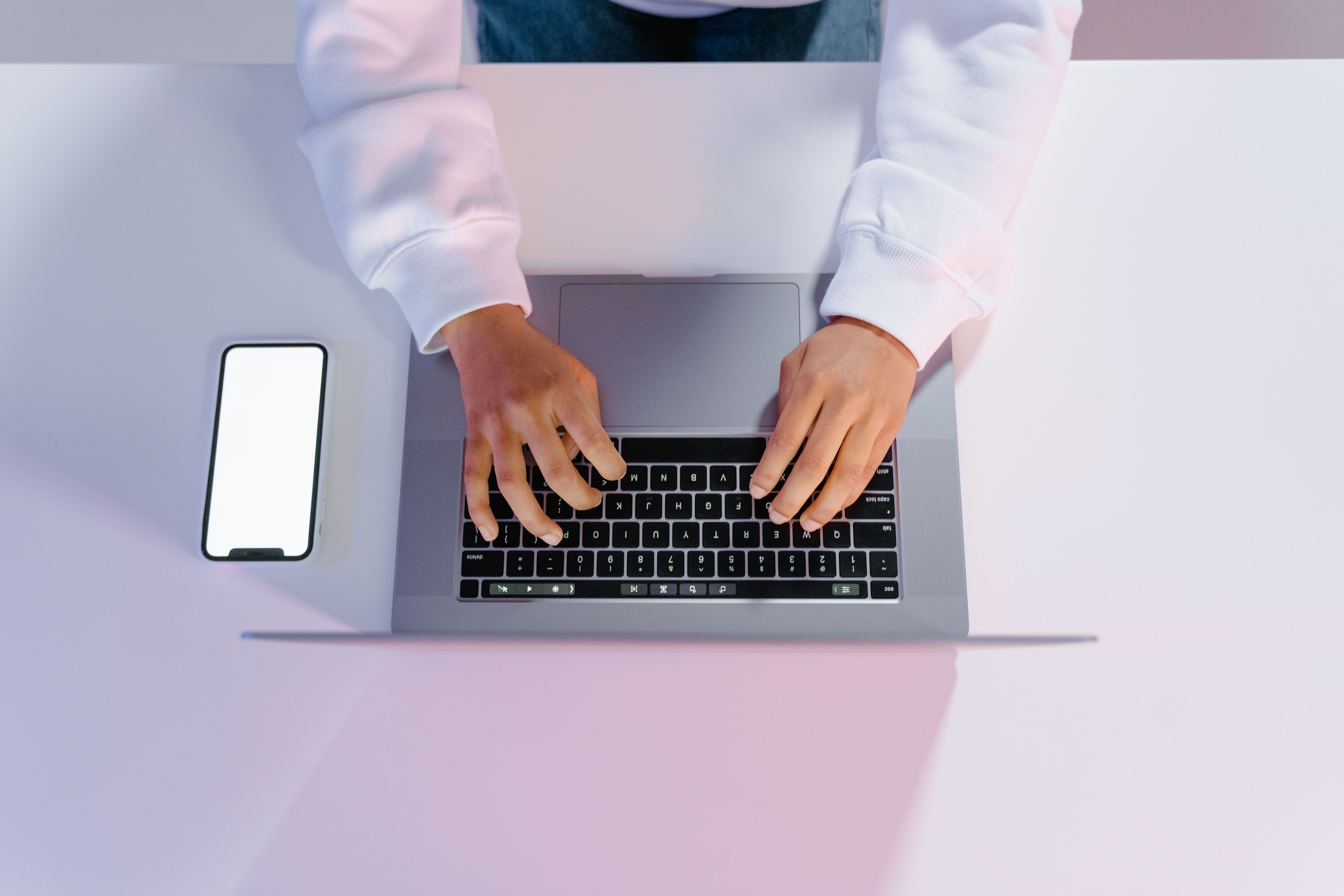 Person using a laptop and smartphone at a desk