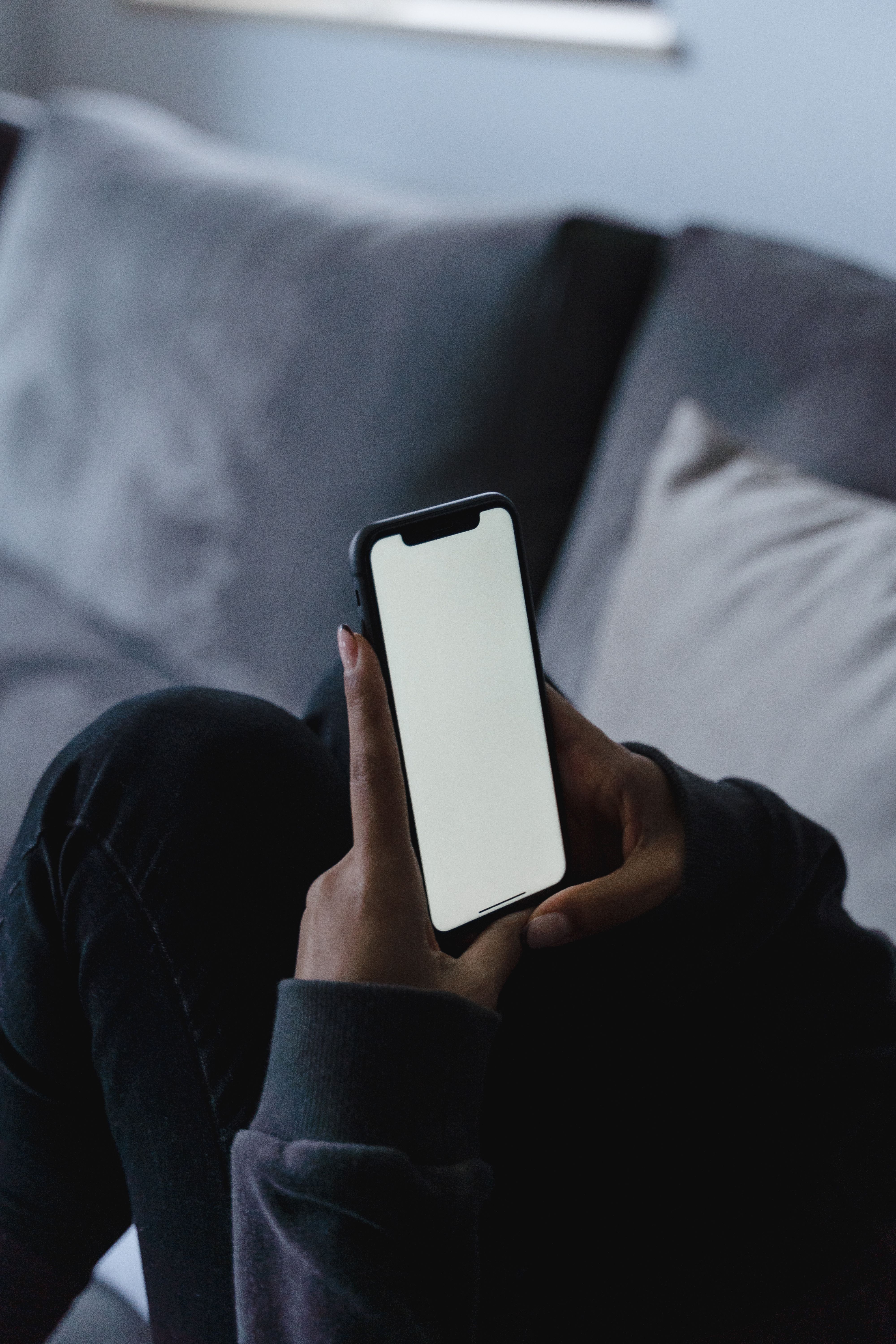 Close-up of hands holding a modern mobile smartphone device in a contemporary living space