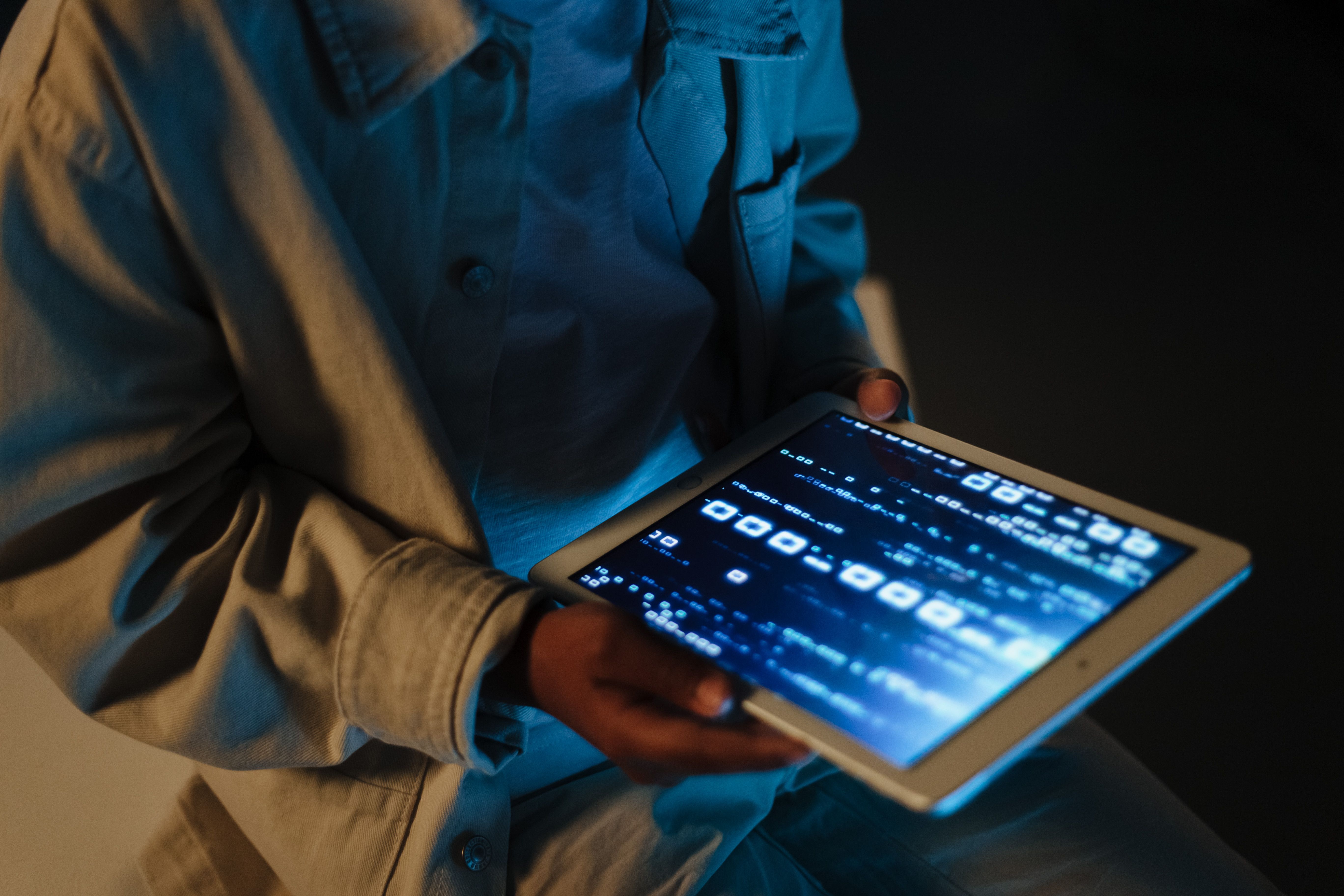 A person using a digital tablet indoors, touching and reviewing interactive screen elements.