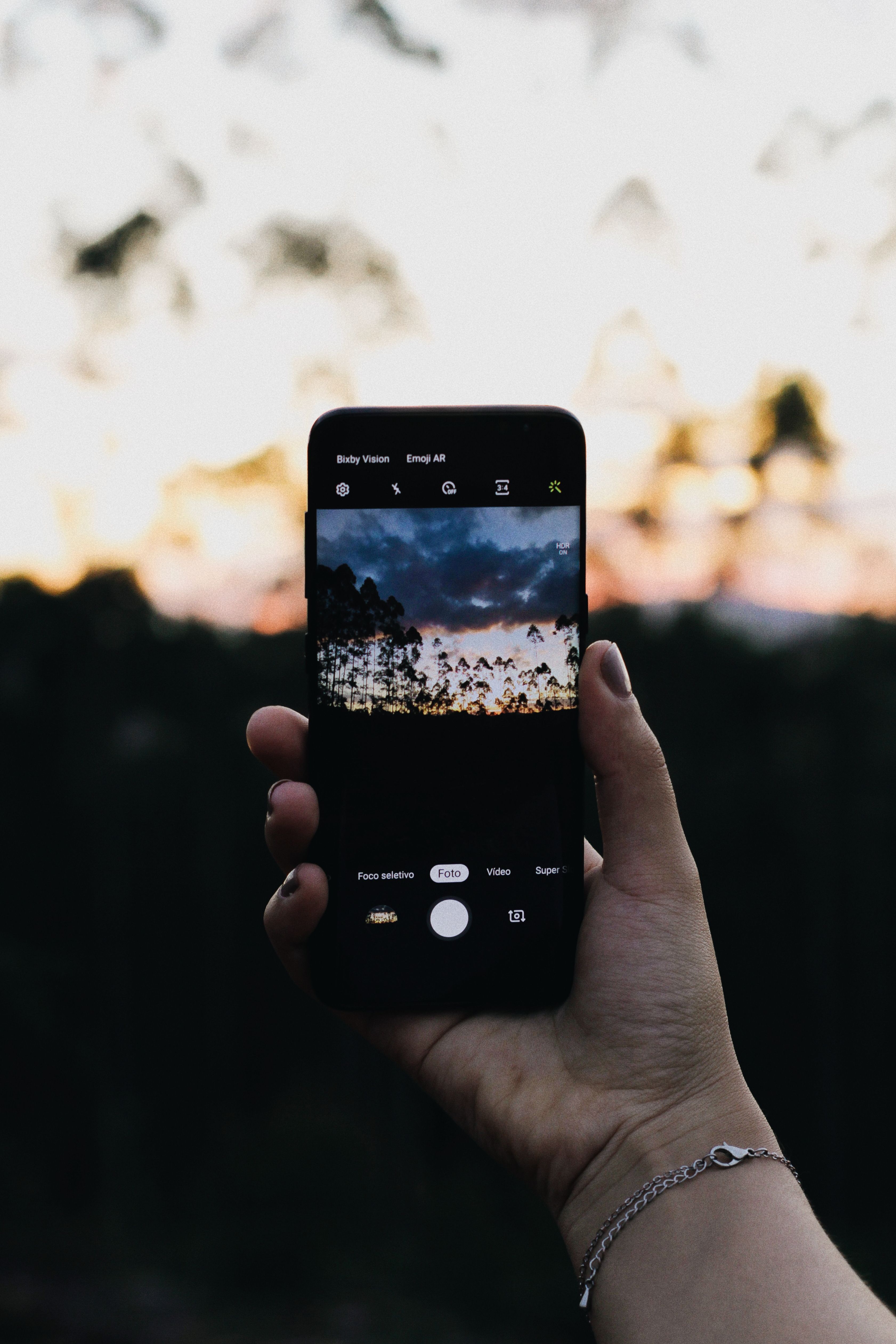A person capturing a scenic sunset using a smartphone, emphasizing modern mobile photography.