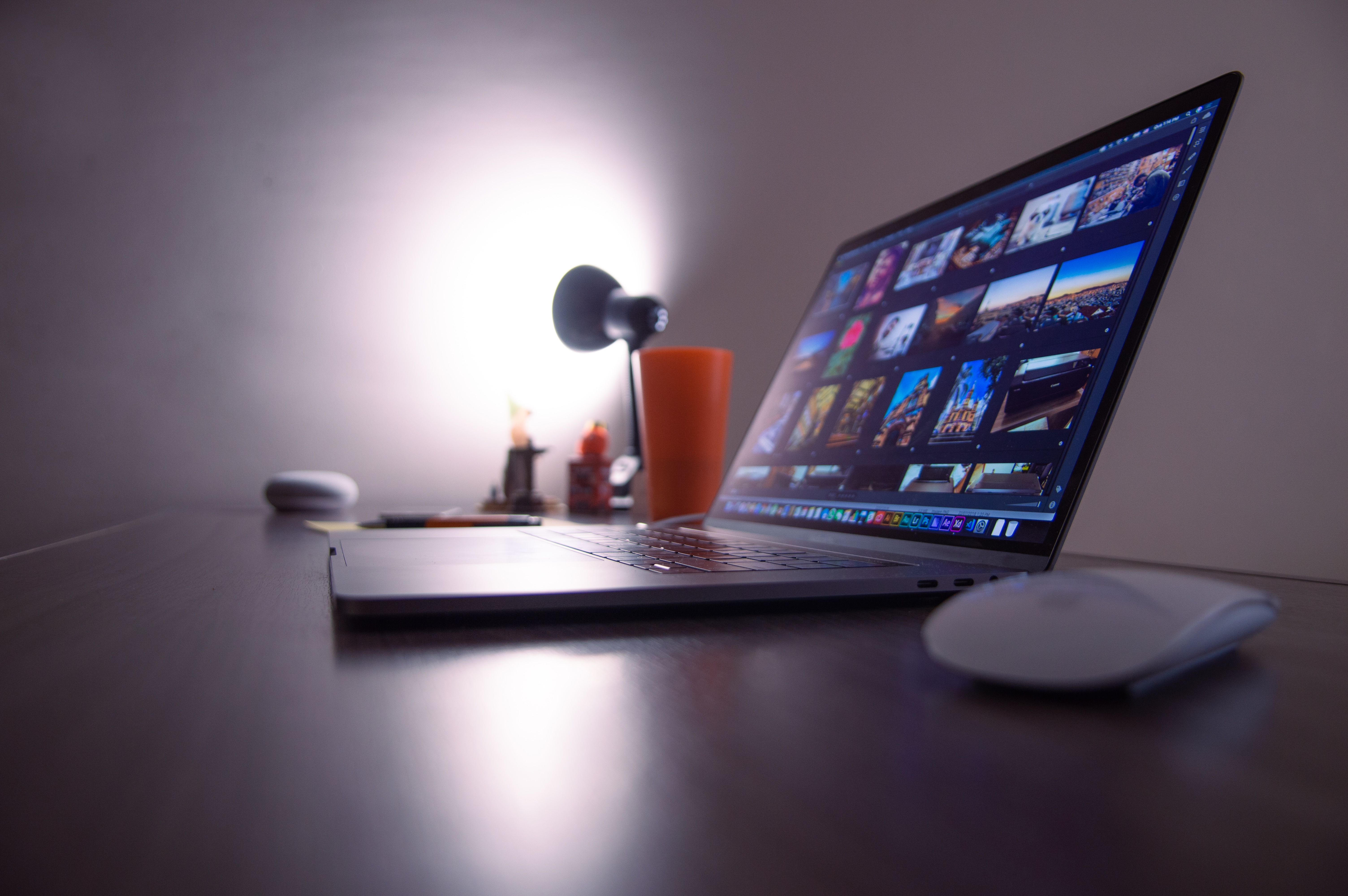 A sleek workspace desk setup featuring a modern laptop computer, desk lamp, and office accessories.