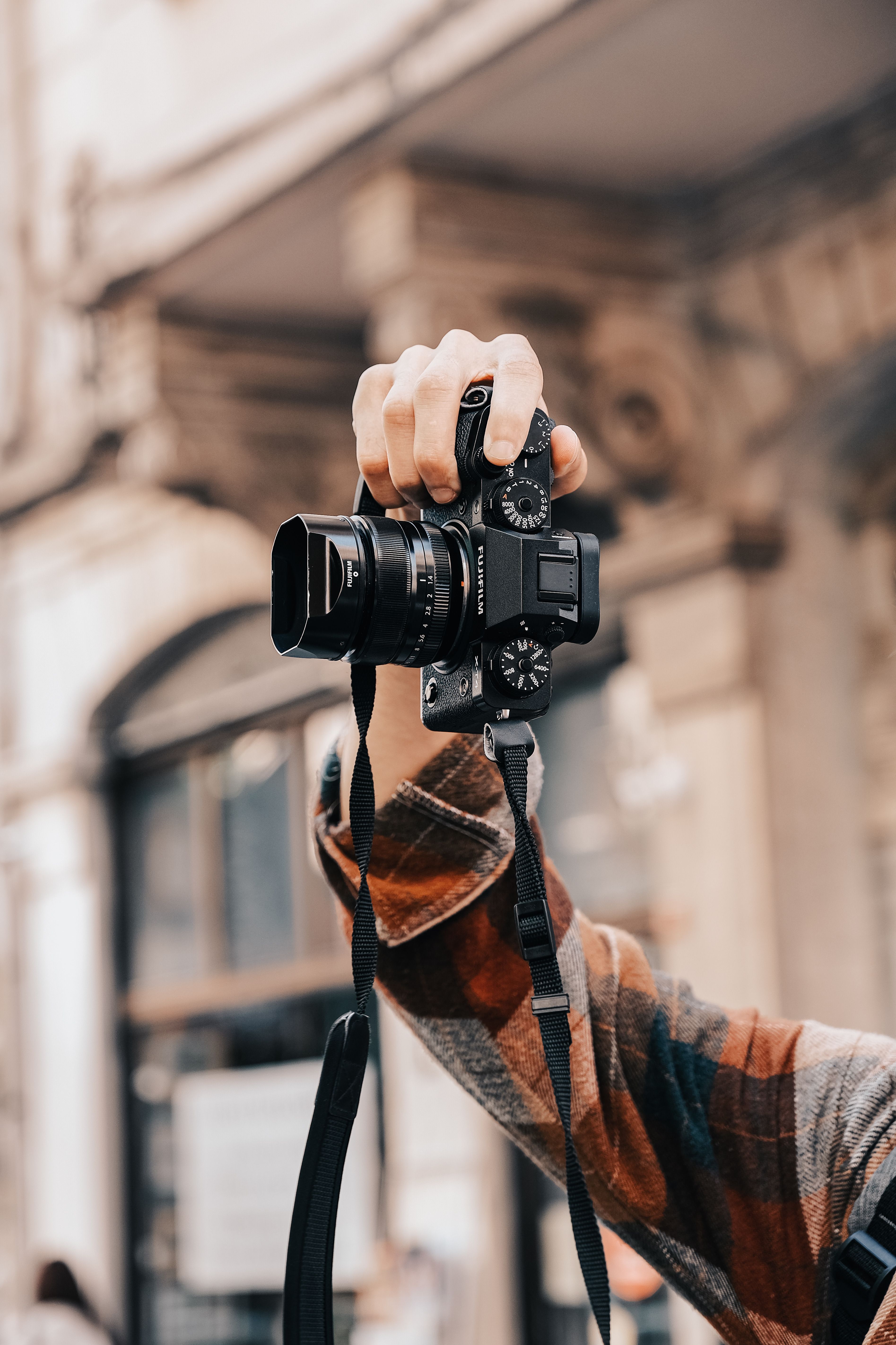 A person holding a camera in an urban setting, generic photographic illustration.