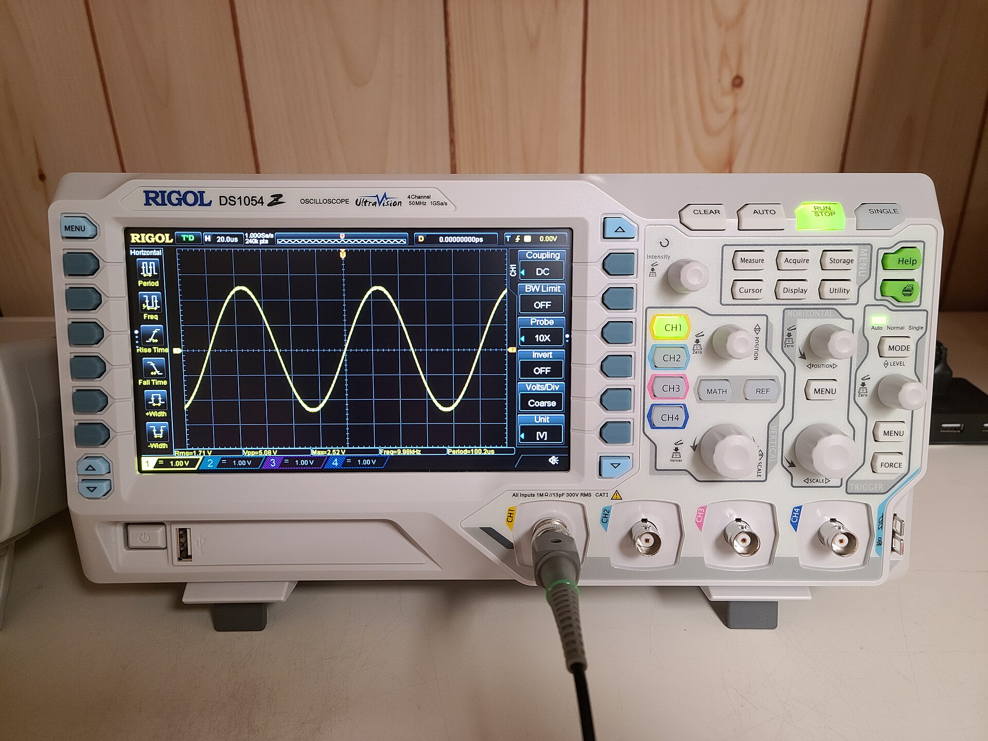 Digital storage oscilloscope on an electronics laboratory workbench displaying real-time signal waveforms.