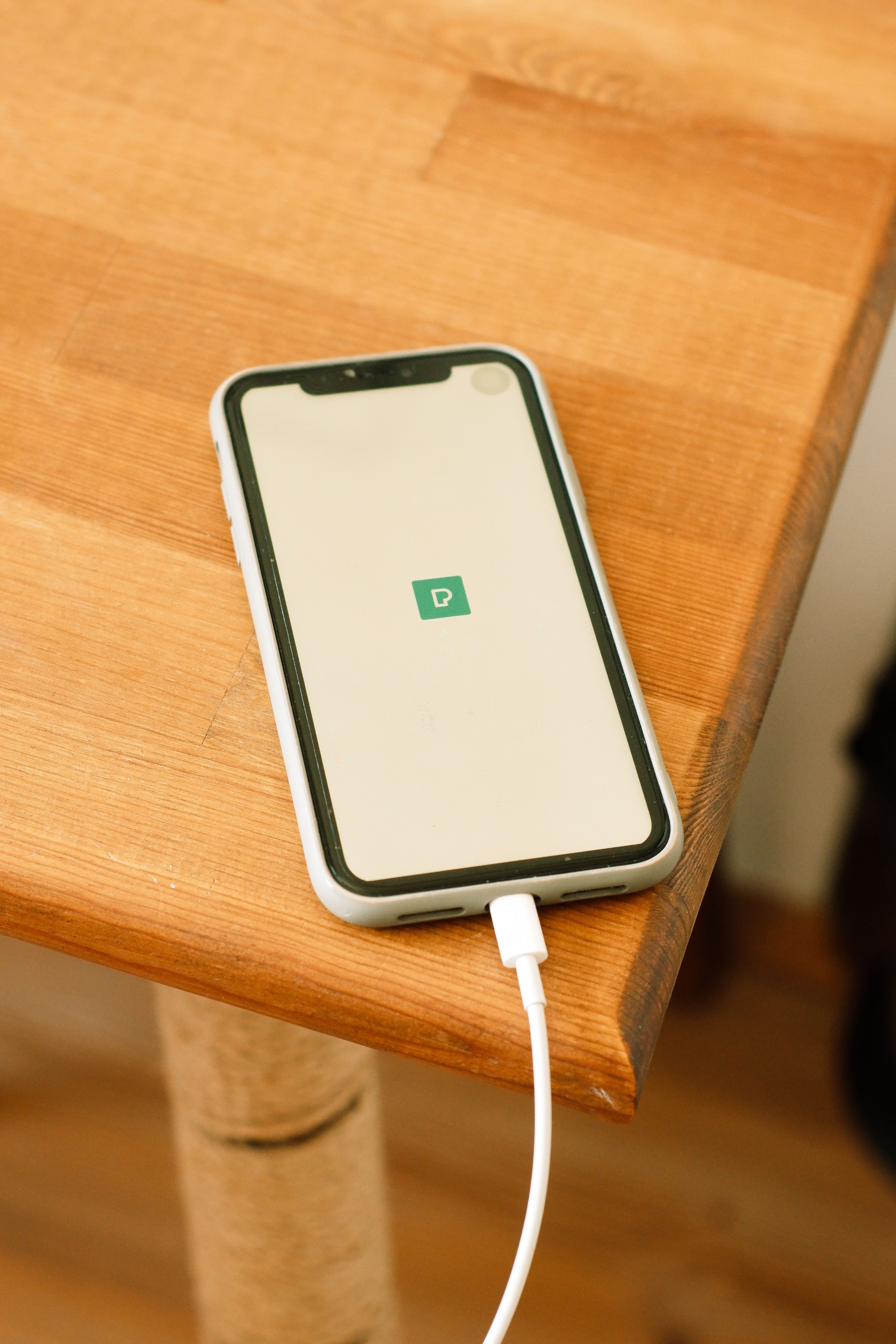 Modern smartphone connected to a fast charger on a wooden desk