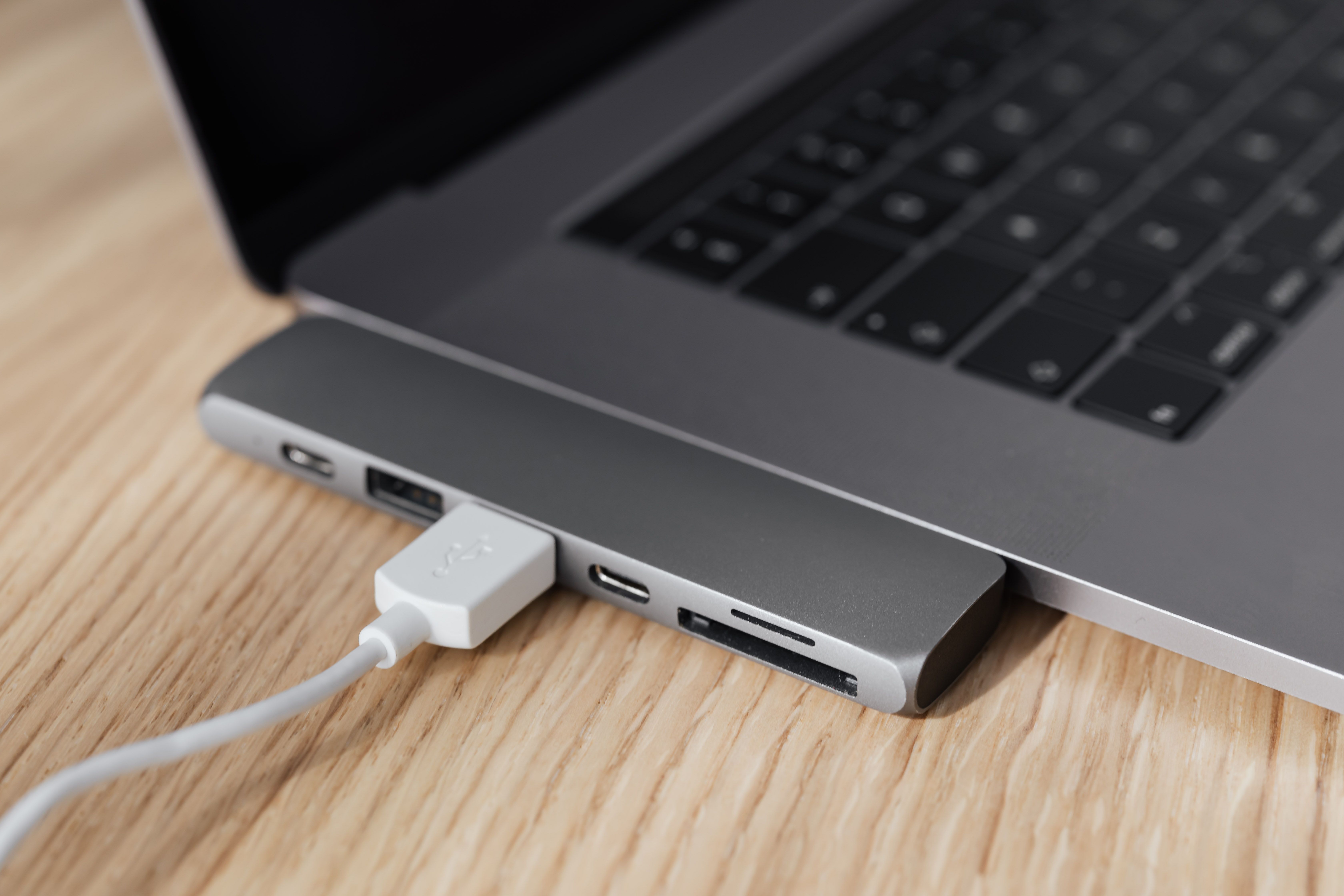 A laptop, USB-C hub and connected cable on a desk.