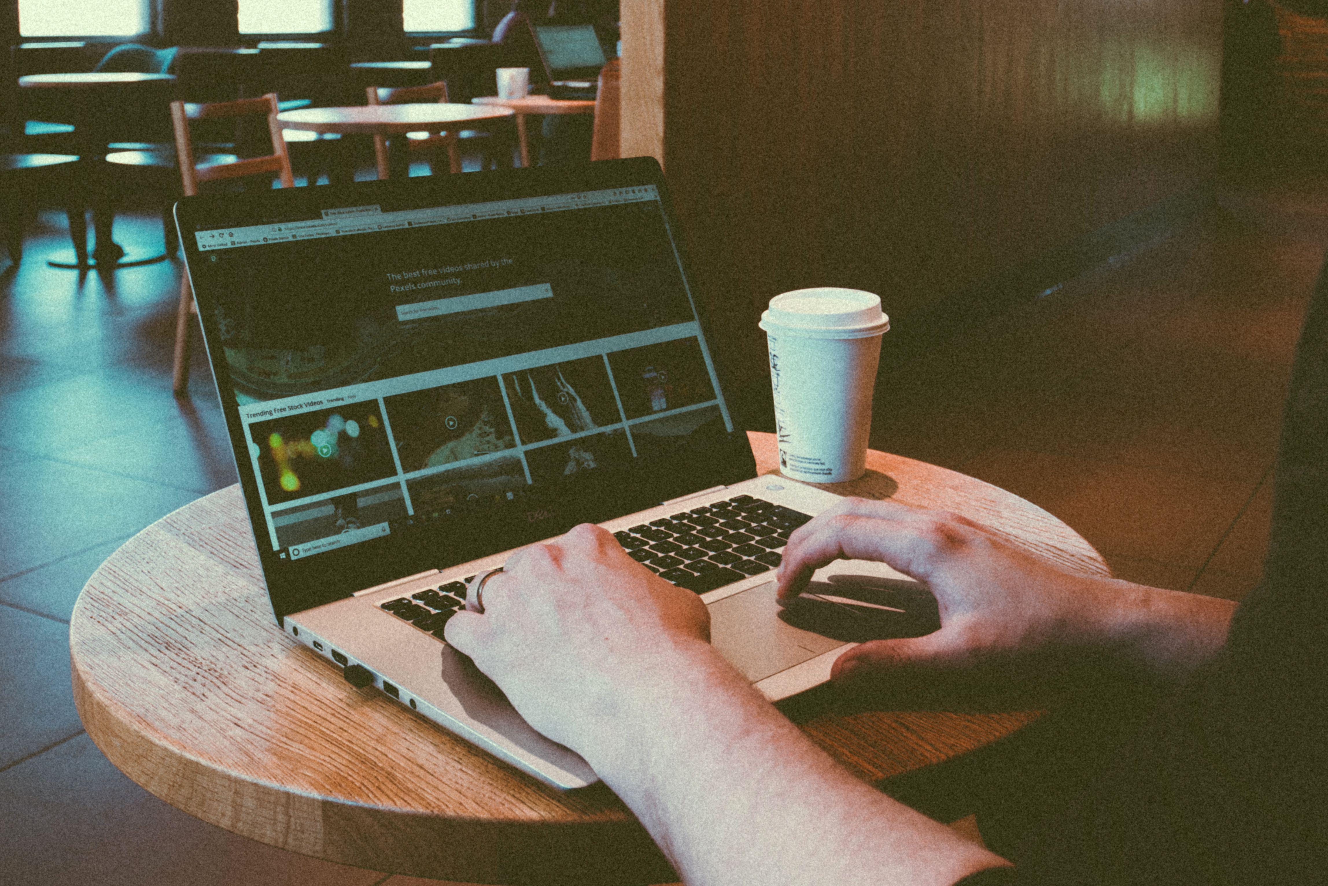 Person typing on a laptop at a coffee table in a cafe