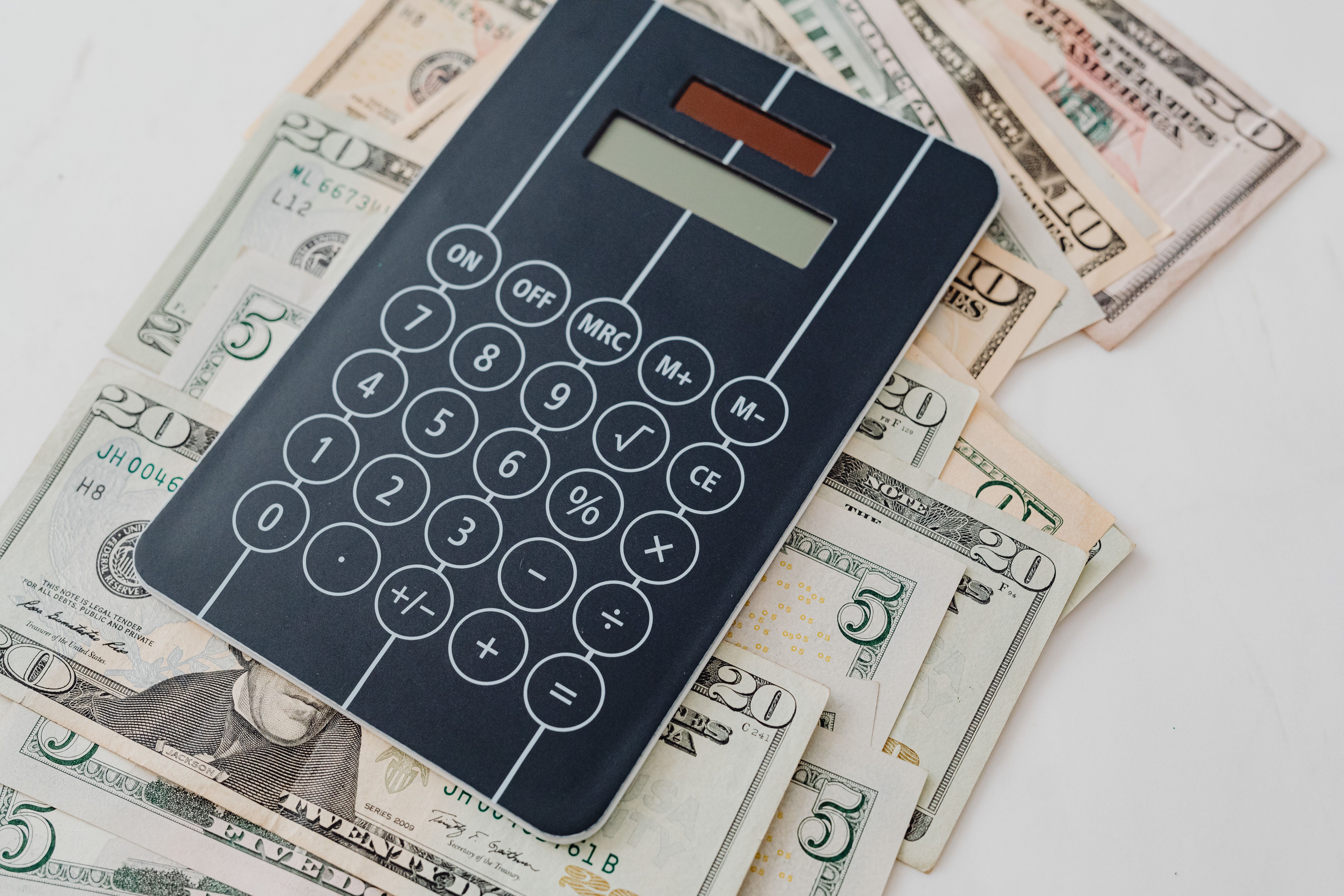 Calculator on top of banknotes, symbolizing cost calculation - illustration