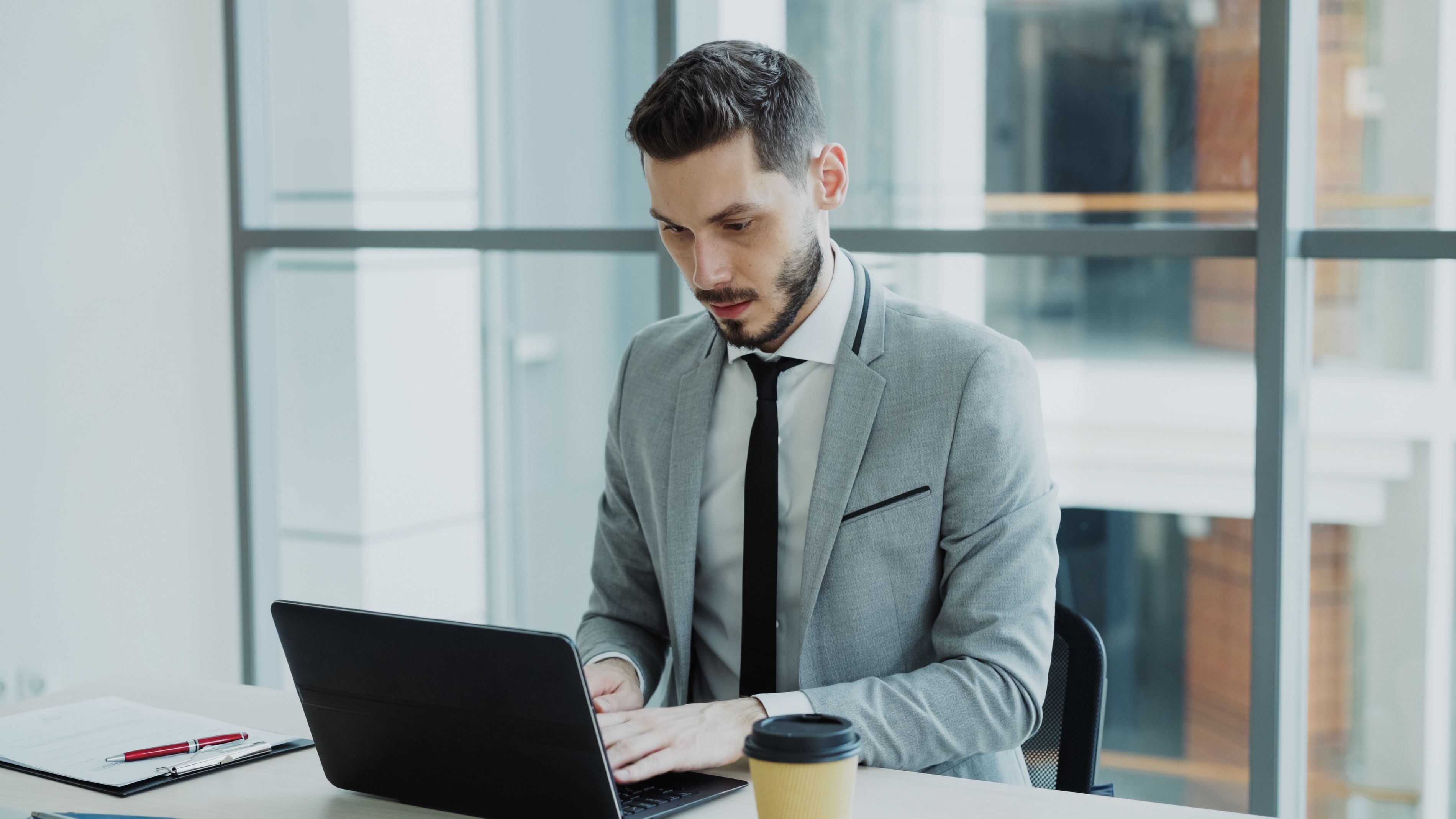 A professional working at a laptop in a bright office environment.